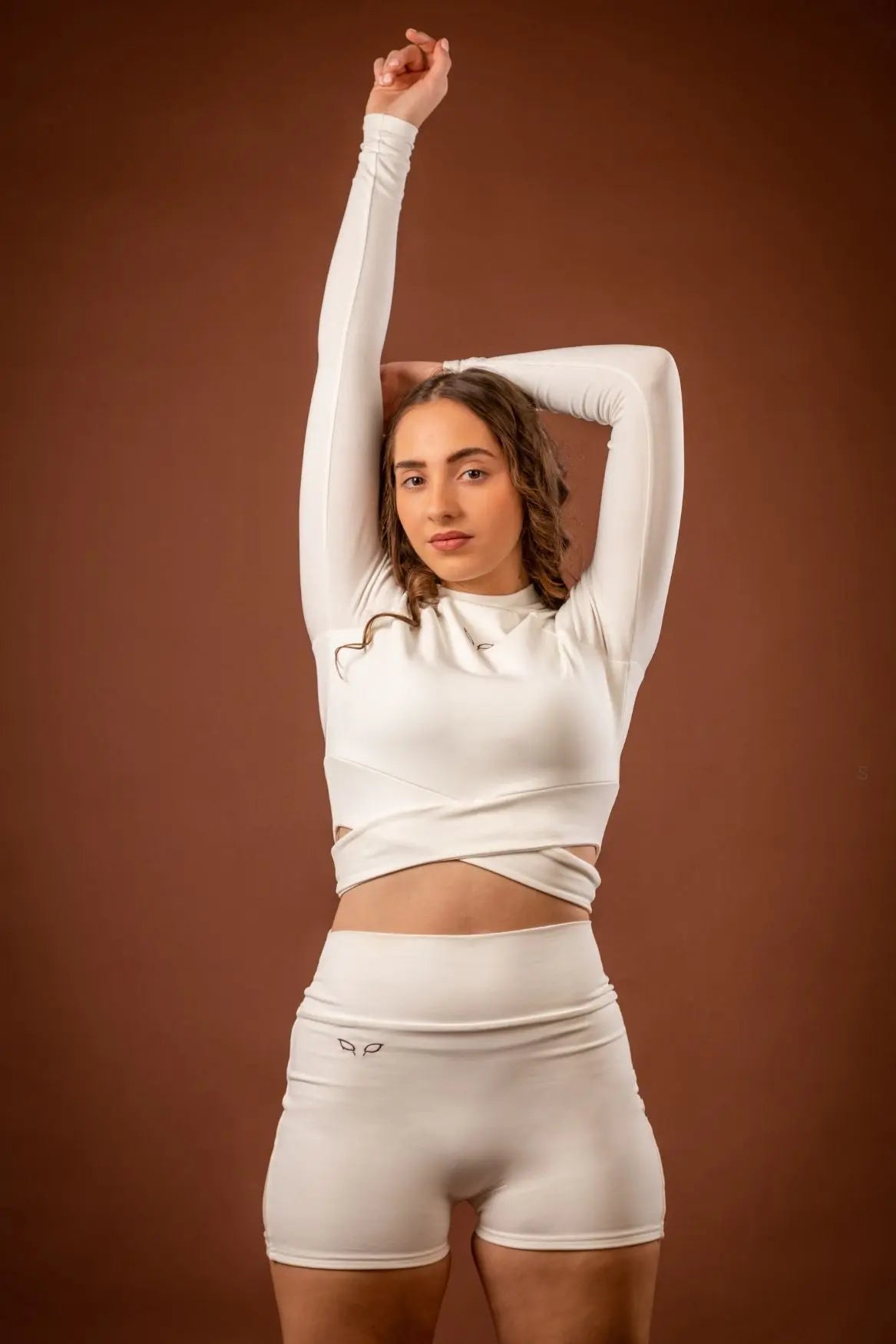 Kairos long-sleeve top and Yuuki lined shorts, a women's sportswear and activewear symbiotic outfit, crafted from sustainable and biosourced seaweed and wood fibers, with biodegradable elastane, free from toxic synthetics, eternal pollutants, and dyes, featuring the natural luminous color of the fibers in a white undyed off-white shade.